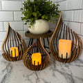 Handcrafted teardrop wooden candle holder with hollow design casting delicate shadows, available in small, medium, and l