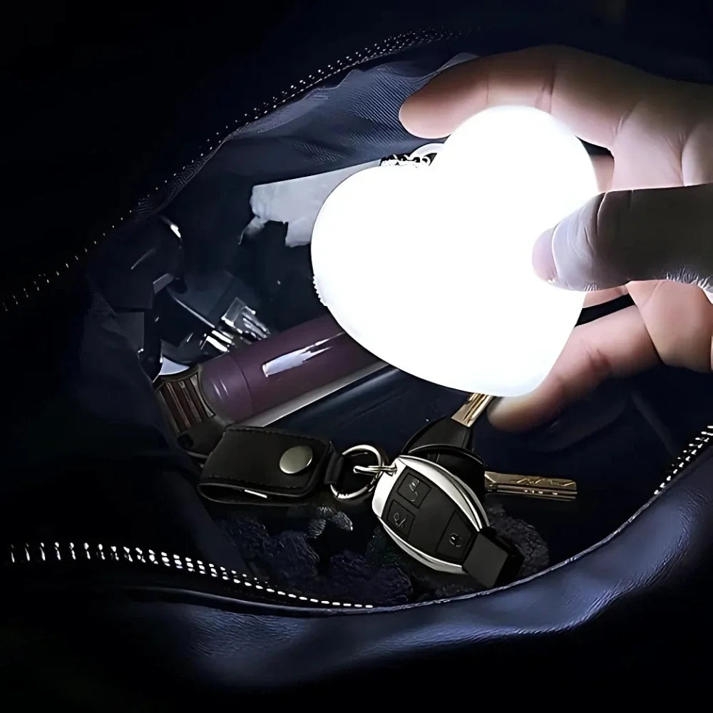 Compact touch-activated purse light illuminating a dark handbag interior.