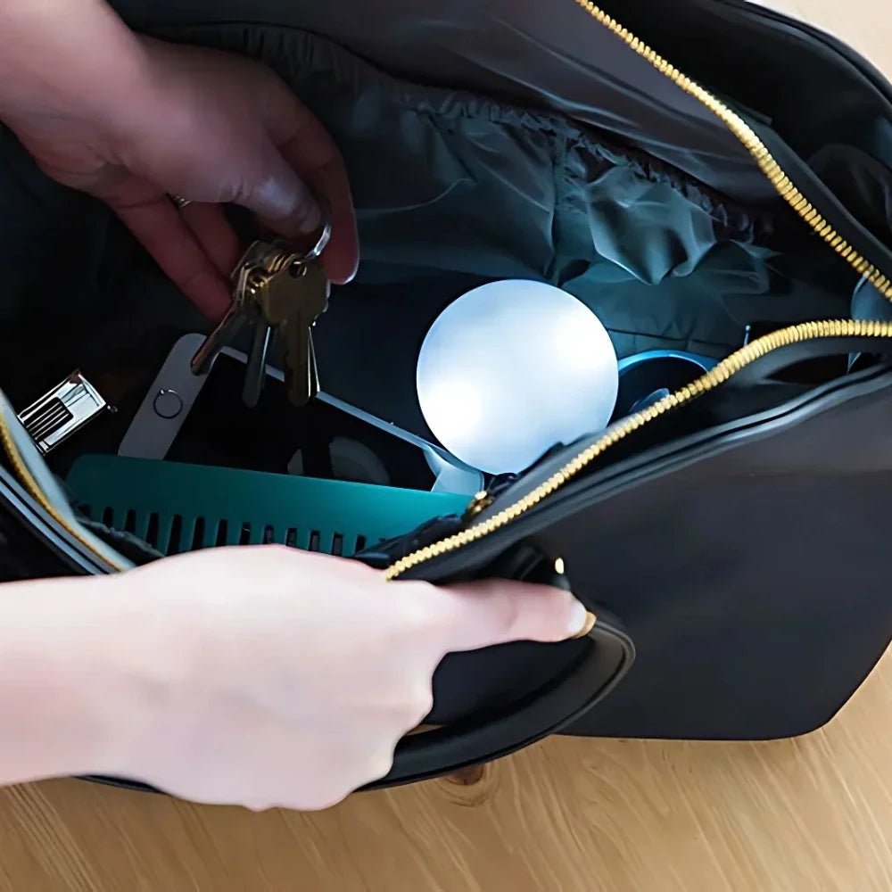 Compact touch-activated purse light illuminating a dark handbag interior. 2