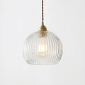 Elegant ribbed glass globe pendant lamp with brass canopy and twisted cable.