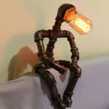 Sculptural Steampunk Sentinel Light crafted from iron pipes with exposed vintage bulb
